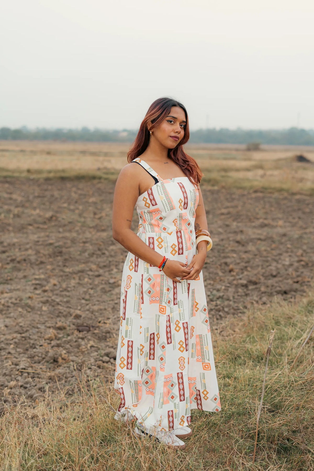 Woman modeling modern sleeveless dresses in geometric, plaid, palm print, and textured blue designs outdoors