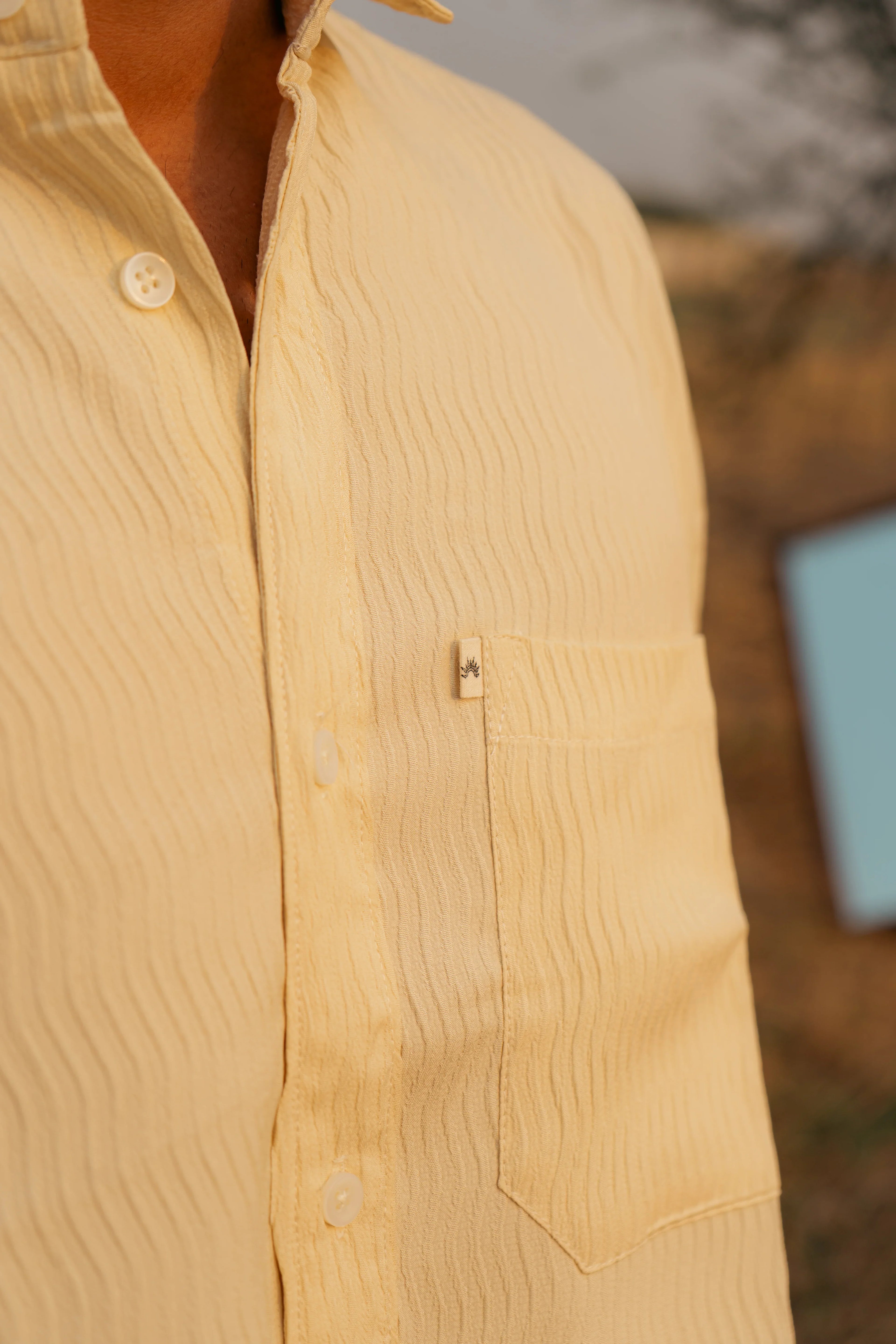 Close-up of cream textured button-up shirt with chest pocket and subtle label detail