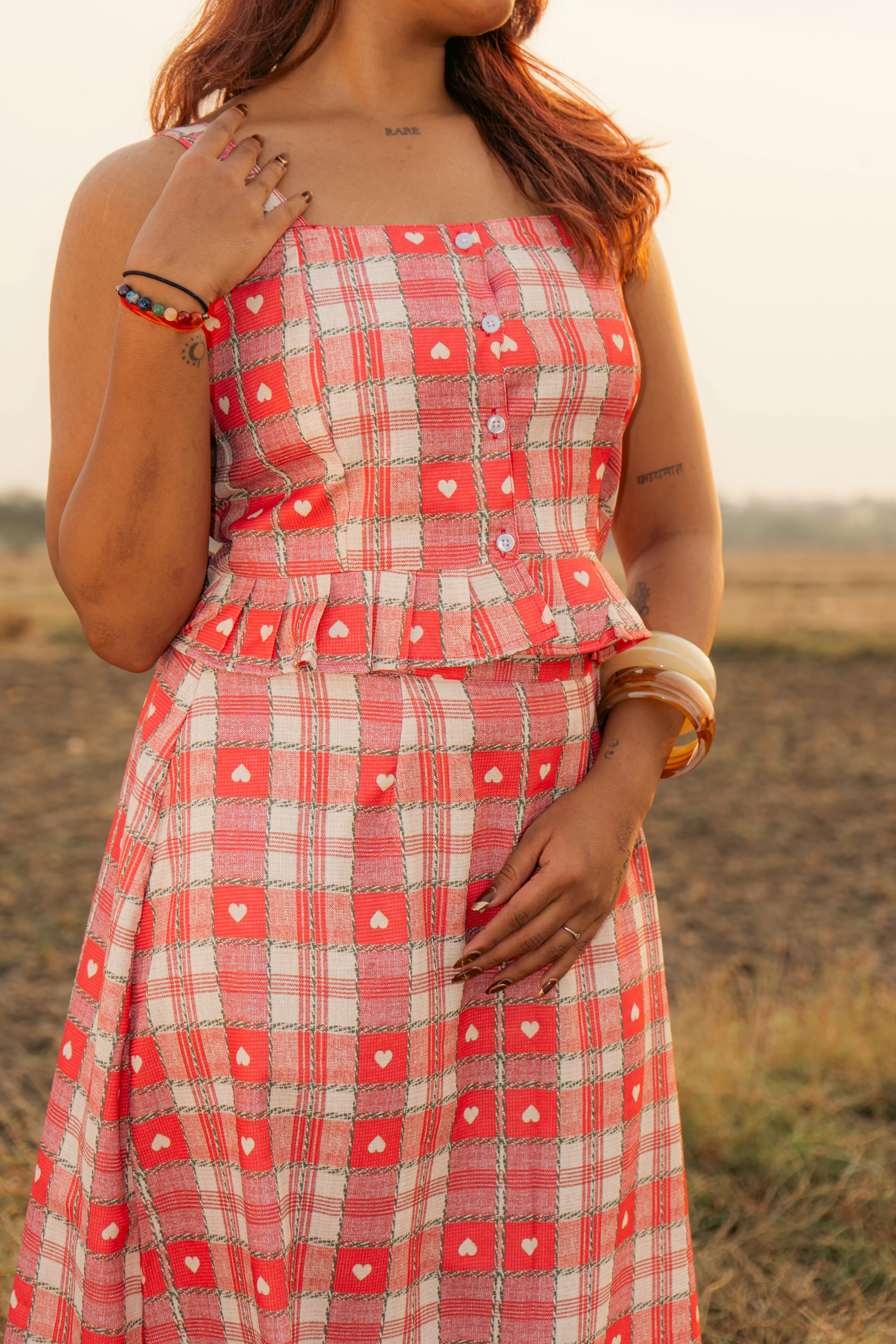 Woman wearing red plaid sleeveless dress with heart patterns and button details outdoors