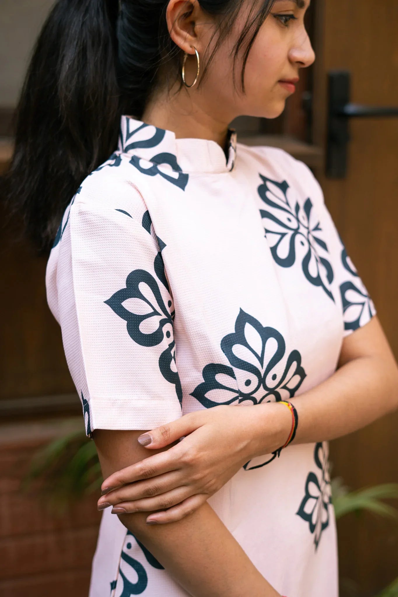 Woman in a light pink dress with bold black floral prints and short sleeves
